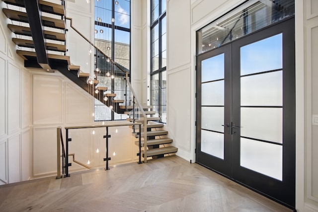 foyer entrance featuring french doors, a high ceiling, stairs, and a decorative wall
