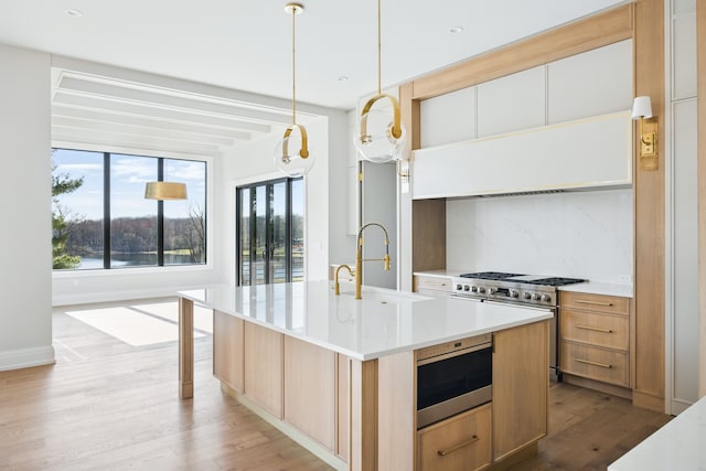 kitchen with a sink, healthy amount of natural light, light wood-type flooring, light countertops, and recessed lighting