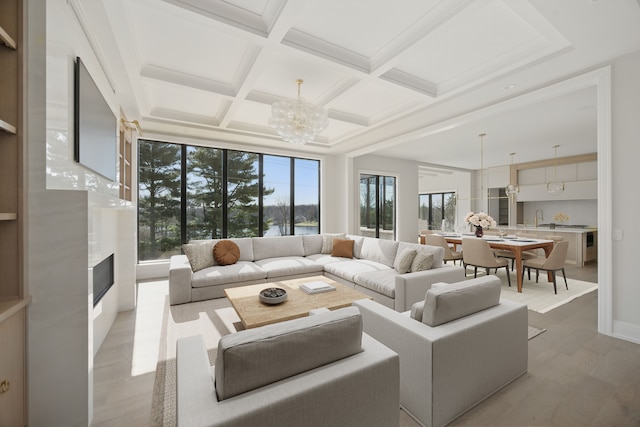 living area featuring a chandelier, wood finished floors, coffered ceiling, beam ceiling, and a premium fireplace
