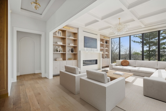3281 Chickering Ln, Bloomfield Hills, MI 48302 - living room featuring a chandelier, a glass covered fireplace, light wood-type flooring, baseboards, and beam ceiling