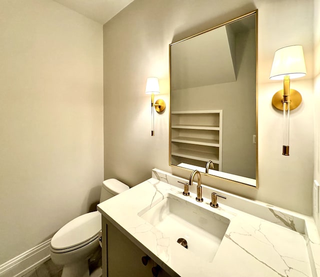 half bath with toilet, vanity, and baseboards
