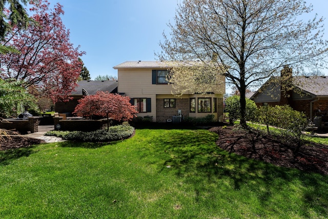 rear view of property with brick siding, outdoor lounge area, central AC unit, a patio, and a yard
