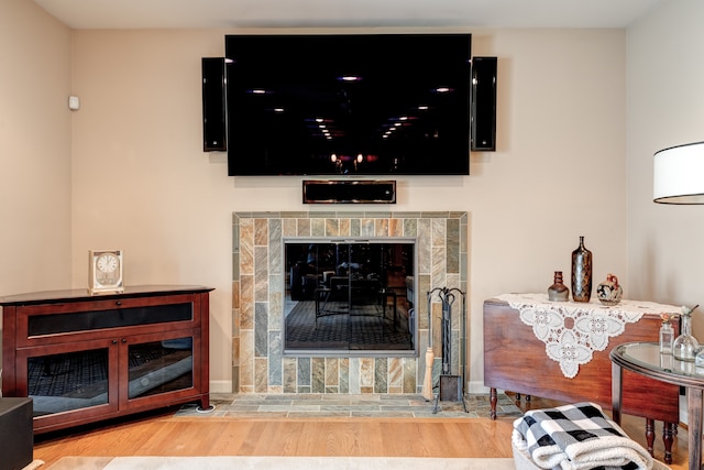 living area featuring baseboards, wood finished floors, and a tile fireplace