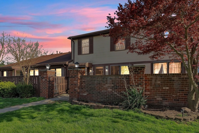 view of front of house featuring brick siding, fence, and a front yard