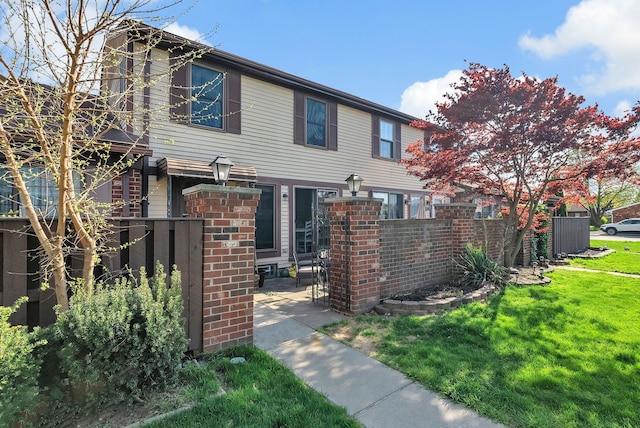 view of front of property with brick siding, a front lawn, and fence