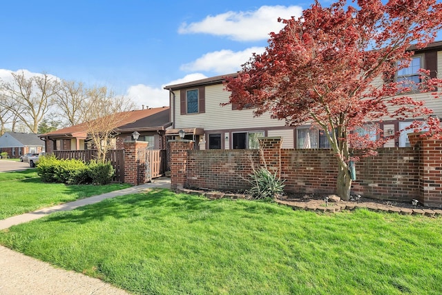 view of front of property featuring brick siding, fence, and a front lawn