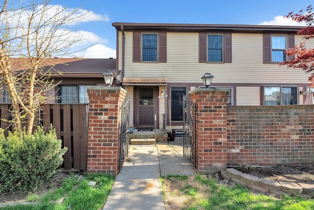 view of front facade with brick siding, fence, and entry steps