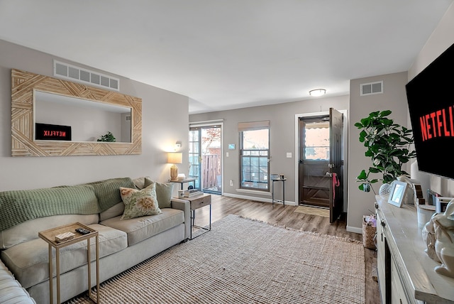 living area with visible vents, baseboards, and wood finished floors
