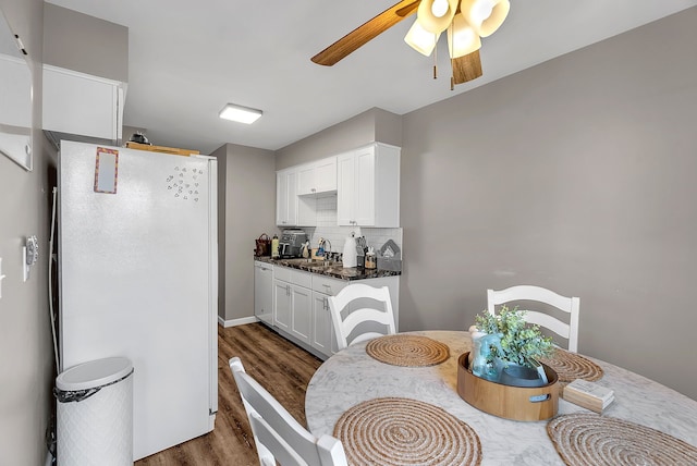 kitchen with freestanding refrigerator, dark wood-style flooring, white cabinetry, tasteful backsplash, and a ceiling fan