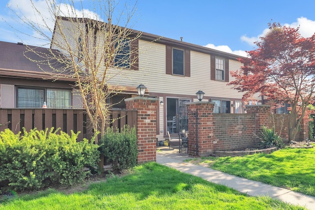view of front of house with fence, brick siding, and a front yard