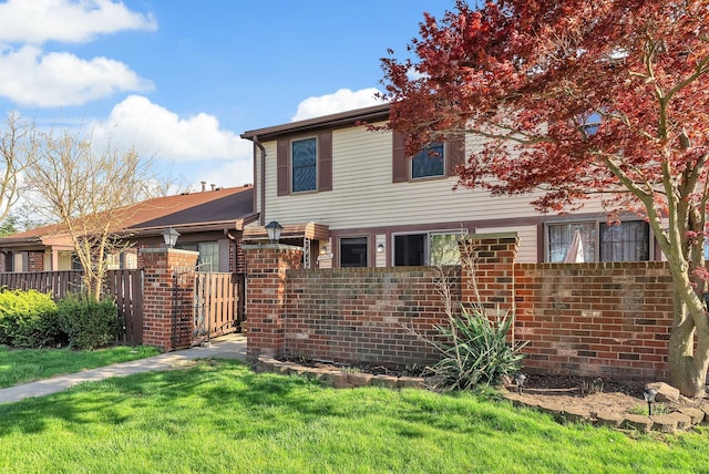 view of front facade with brick siding, fence, and a front yard