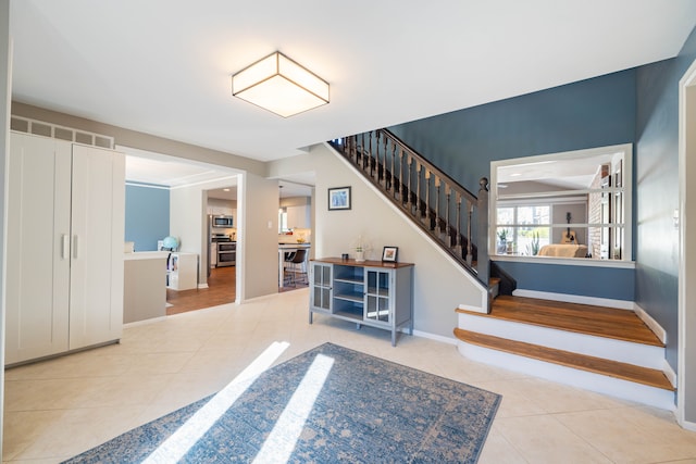 tiled entrance foyer featuring baseboards and stairs