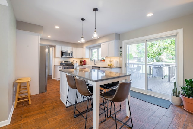 kitchen featuring appliances with stainless steel finishes, white cabinets, a breakfast bar area, and dark wood-style floors