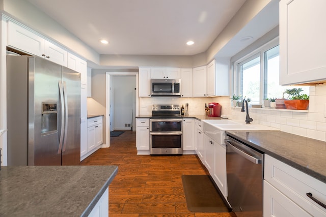 kitchen with white cabinets, appliances with stainless steel finishes, dark wood-style floors, and a sink
