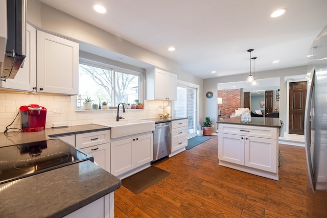 kitchen with backsplash, dark wood-style flooring, a sink, white cabinets, and stainless steel appliances