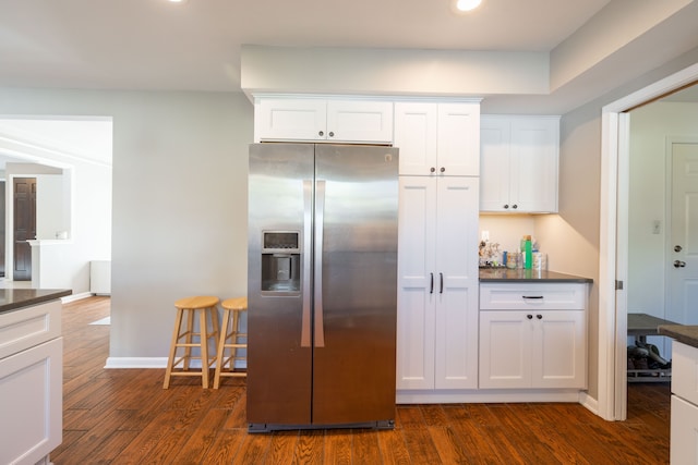 kitchen featuring stainless steel refrigerator with ice dispenser, dark wood-style flooring, dark countertops, and white cabinetry