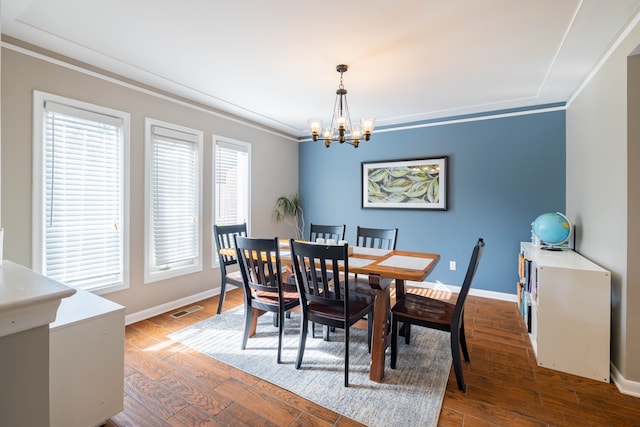dining area featuring crown molding, visible vents, baseboards, a chandelier, and dark wood finished floors