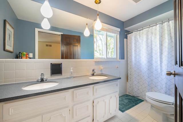 full bathroom featuring a sink, tile patterned floors, toilet, and double vanity
