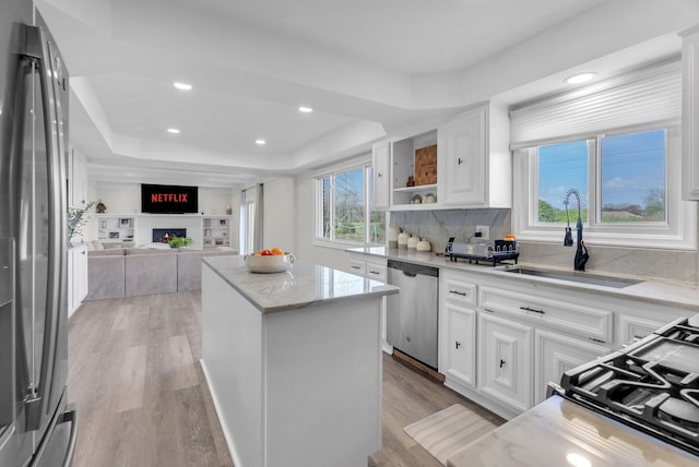 kitchen with a sink, a center island, stainless steel appliances, and light wood-style flooring