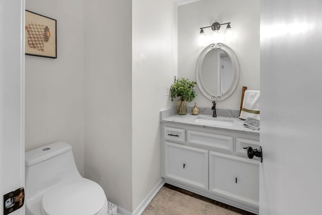 half bath featuring vanity, baseboards, and toilet