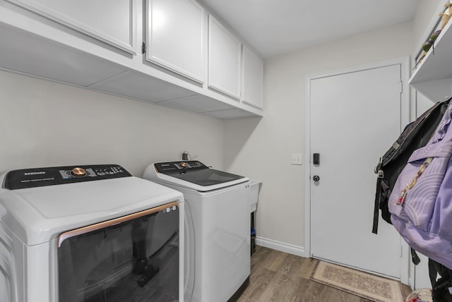 clothes washing area with wood finished floors, baseboards, cabinet space, and washing machine and dryer