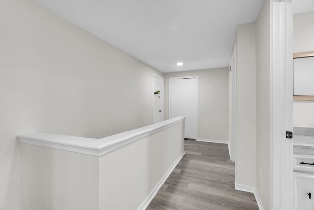 hallway featuring baseboards, recessed lighting, and wood finished floors