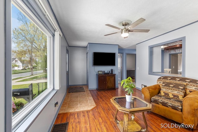 living room with plenty of natural light, ceiling fan, wood finished floors, and visible vents
