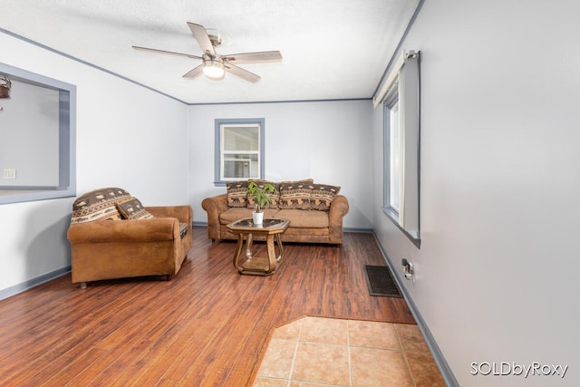 living area featuring visible vents, a ceiling fan, baseboards, and wood finished floors