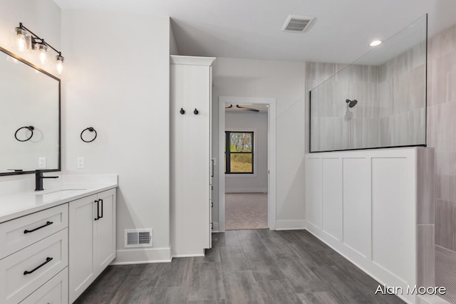 full bath featuring visible vents, walk in shower, wood finished floors, and vanity