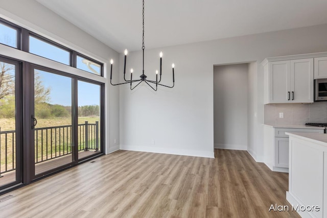 unfurnished dining area featuring baseboards, visible vents, light wood finished floors, and a chandelier