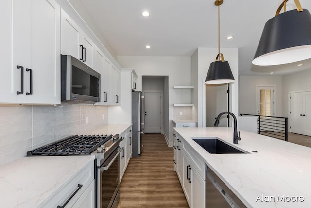 kitchen with open shelves, wood finished floors, a sink, stainless steel appliances, and white cabinetry