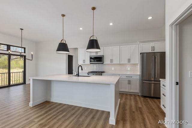 kitchen with wood finished floors, light countertops, white cabinets, tasteful backsplash, and stainless steel appliances