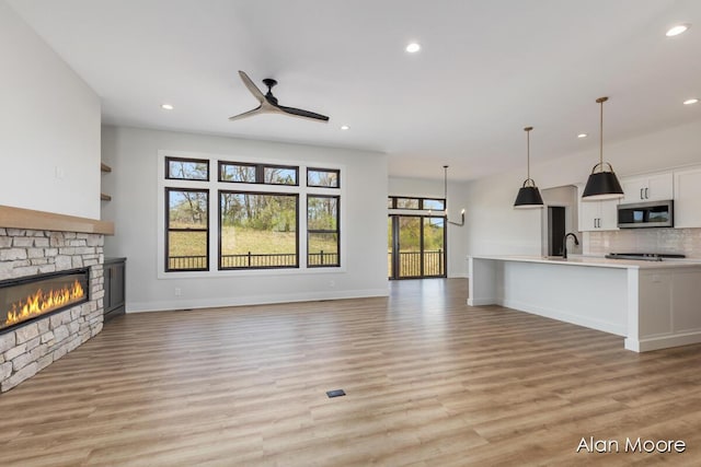 unfurnished living room featuring a fireplace, baseboards, ceiling fan, light wood-type flooring, and recessed lighting