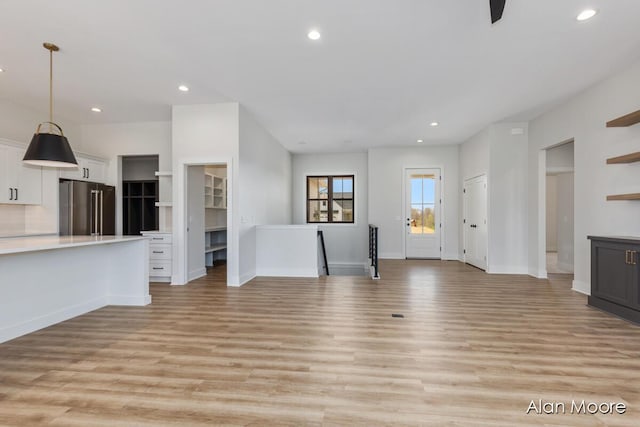 unfurnished living room with recessed lighting, baseboards, and light wood-type flooring
