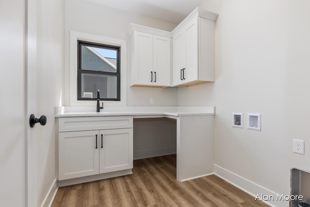 laundry area featuring cabinet space, a sink, hookup for a washing machine, light wood-style floors, and baseboards