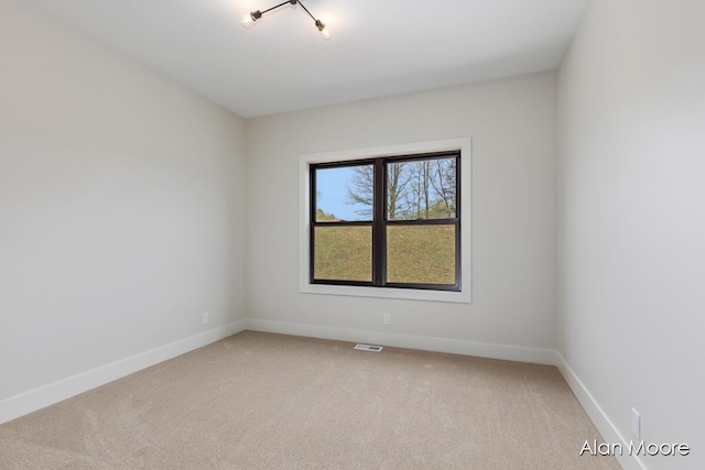 empty room with light colored carpet, baseboards, and visible vents