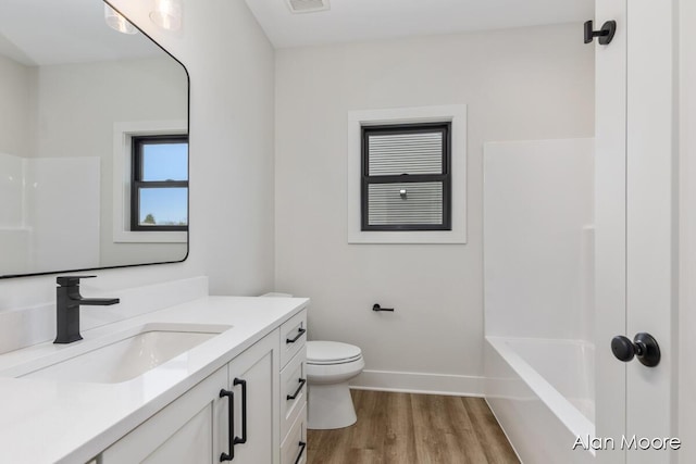 bathroom with vanity, toilet, baseboards, wood finished floors, and visible vents