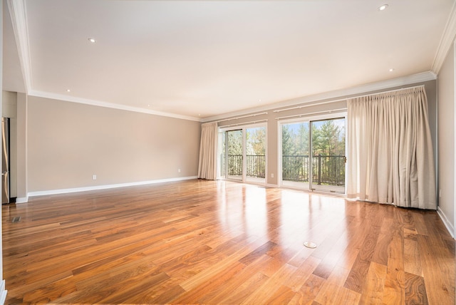 spare room featuring crown molding, baseboards, and light wood finished floors