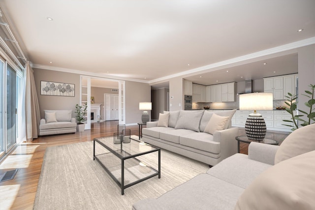 living area featuring baseboards, visible vents, ornamental molding, and light wood-style flooring