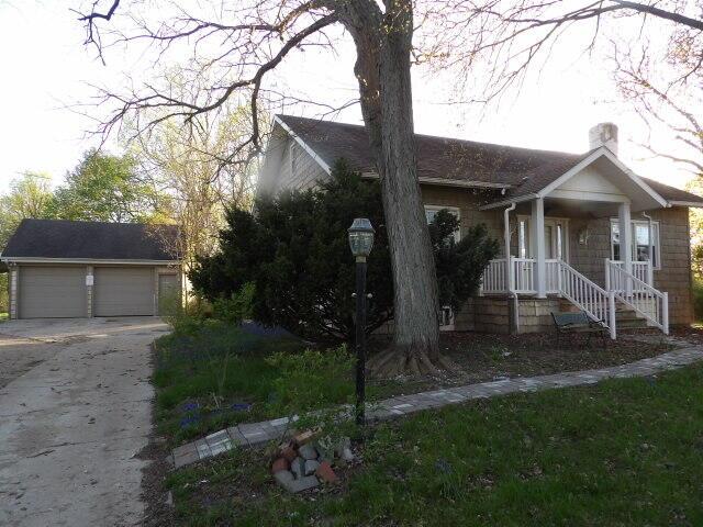view of front facade with a garage, an outbuilding, and a chimney
