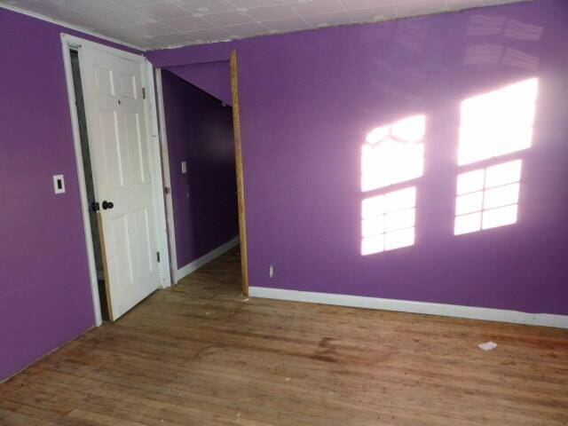 unfurnished room with baseboards and wood finished floors