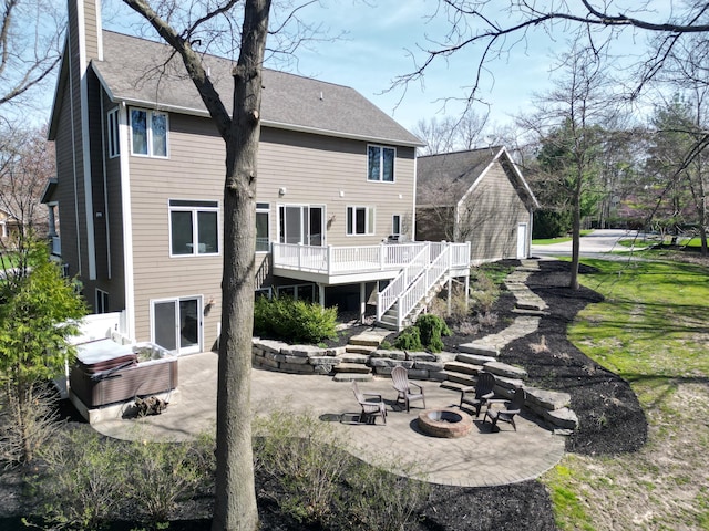 rear view of house with a chimney, a deck, stairway, a patio, and a fire pit