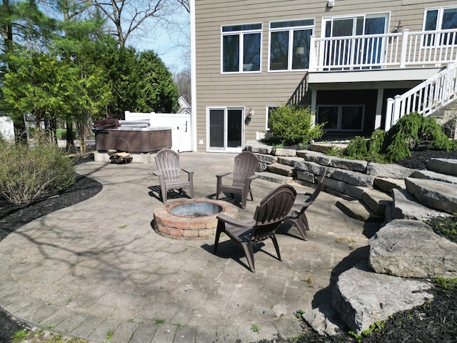 view of patio with stairs, a hot tub, and an outdoor fire pit