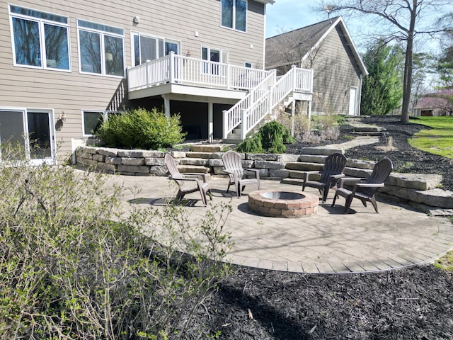 back of house featuring stairs, an outdoor fire pit, a deck, and a patio
