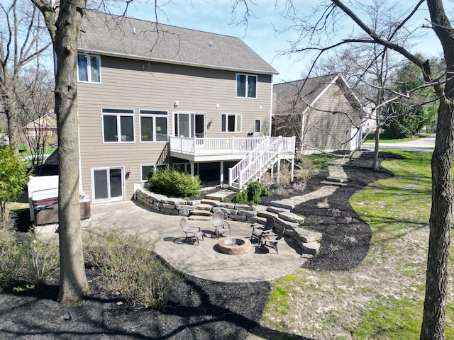 rear view of property featuring roof with shingles, a deck, a patio area, stairway, and a fire pit