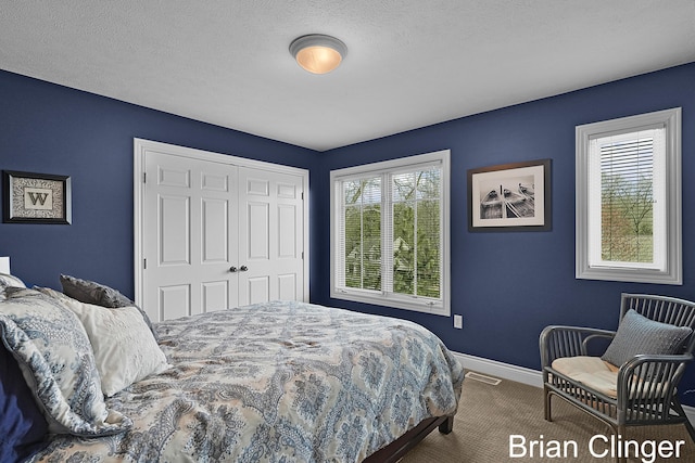 carpeted bedroom with baseboards, a closet, a textured ceiling, and visible vents