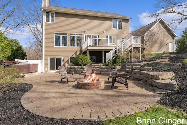 back of house featuring a hot tub, a deck, stairway, a patio area, and a fire pit