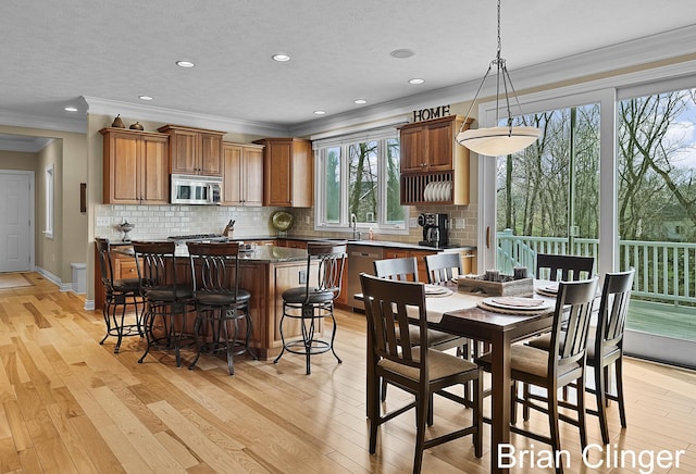dining room with crown molding, baseboards, recessed lighting, and light wood finished floors