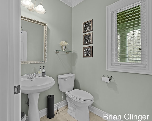 half bathroom featuring crown molding, toilet, and baseboards