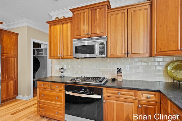 kitchen featuring crown molding, brown cabinetry, tasteful backsplash, light wood finished floors, and appliances with stainless steel finishes